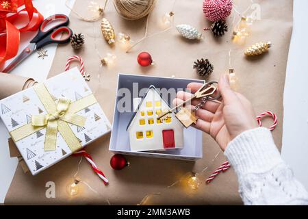 Schlüssel zum Haus mit Schlüsselanhänger auf gemütlichem Zuhause in Geschenkbox mit Weihnachtsdekor-Verpackung. Pack ein Geschenk für Neujahr, Weihnachten. Gebäude, Projekt, Umzug nach Stockfoto