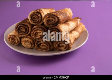 Foto von gebratenen, dünnen Pfannkuchen in Nahaufnahme auf farbigem Hintergrund Stockfoto