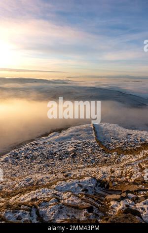 Vom Gipfel des Pen-y-gent Berges bei Sonnenaufgang mit Nebel und Schnee im Yorkshire Dales National Park, en, blickt ihr auf den letzten verschneiten Pfad Stockfoto