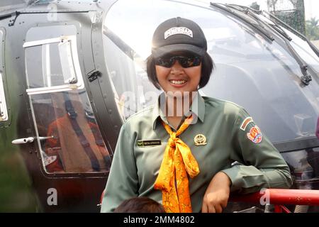 Porträt einer Pilotin der indonesischen Armee, sie trägt eine Sonnenbrille, lächelt für die Kamera und posiert vor dem Hubschrauber. Stockfoto