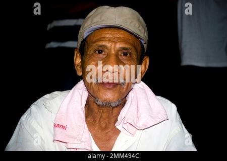 Porträt eines alten Mannes aus Indonesien, er sieht ernst aus in der Kamera und trägt einen Hut und ein weißes Hemd. Stockfoto