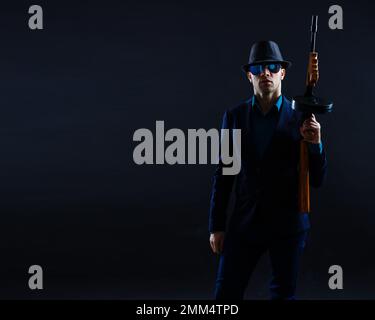 Geschäftsmann mit Sonnenbrille und Maschinengewehr. Stockfoto