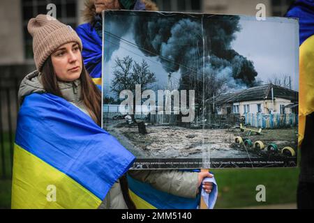 London, Großbritannien. 29. Januar 2023. Eine Frau hält ein Plakat mit einem brennenden Haus und einem leeren Spielplatz vor sich. Demonstranten und Aktivisten versammeln sich gegen Russlands Invasionen in der Ukraine und den Krieg in der Ukraine in ihrem wöchentlichen Protest gegenüber der Downing Street in Whitehall, Westminster, und zwar neben der weiterhin schwierigen Situation und den Nachrichten über erneute Angriffe auf Zivilpersonen, die im ganzen Land leben. Kredit: Imageplotter/Alamy Live News Stockfoto