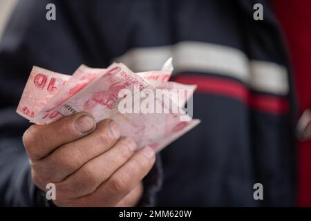 Ankara, Türkei. 29. Januar 2023. Ein Verkäufer hält 10 türkische Lira-Banknoten auf einem Flohmarkt. Der Flohmarkt, der an den Wochenenden auf dem Ankara-Ulus-Platz aufgebaut wird, wurde in den letzten Monaten aufgrund der hohen Inflation in der Türkei von mehr Menschen besucht. Die vom Statistikinstitut der Türkei (TUIK) angekündigte Inflationsrate von 64% wird von vielen unabhängigen Wirtschaftsverbänden als höher eingeschätzt. Kredit: SOPA Images Limited/Alamy Live News Stockfoto