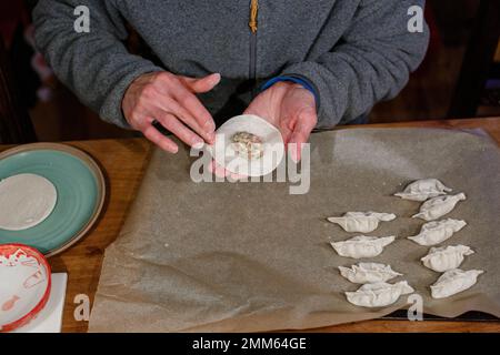 Nahaufnahme eines Mannes, der eine Platte chinesischer Knödel bildet Stockfoto
