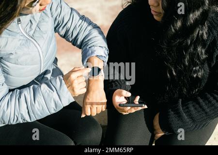 Zwei Freundinnen, die sich über soziale Medien unterhalten und SMS schreiben Stockfoto