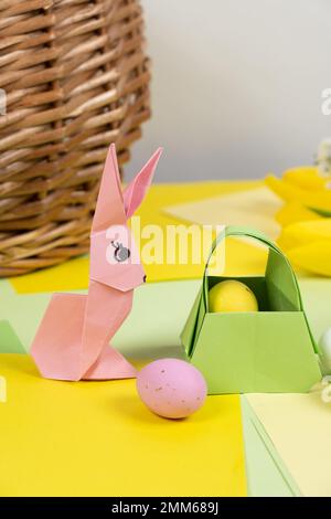 An easter bunny figurine made of paper, origami, and a basket with eggs, happy easter. Stock Photo