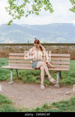 Eine weiße Frau stillt ihr kleines Mädchen im Park von Bergamo Stockfoto