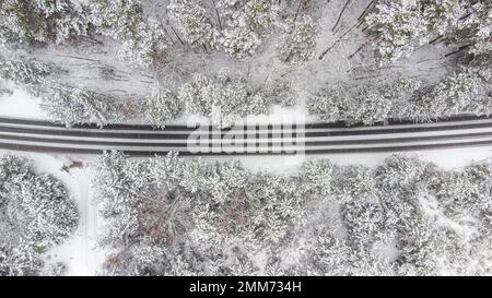 Luftaufnahme des Winterwaldes und der Straße. Vogelperspektive Stockfoto