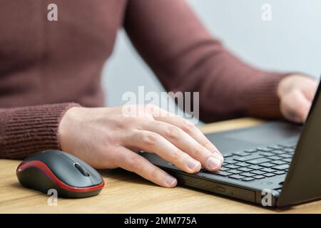 Nahaufnahme eines Mannes, der im Büro an einem Laptop arbeitet. Büromitarbeiter tippen mit den Händen über die Tastatur. Geschäftsmann, der ein Notebook verwendet Stockfoto