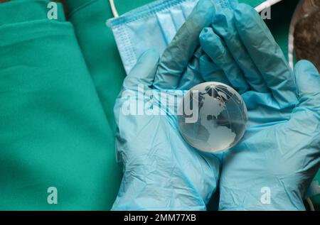 Hände in medizinischen Handschuhen mit einem Globus Stockfoto