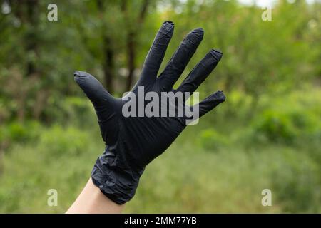 Hand in medizinische Handschuhe auf einem verschwommenen Hintergrund auf der Straße Stockfoto