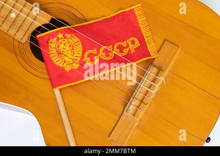 Rote Flagge der UdSSR auf einem Stock und Gitarre auf weißem Hintergrund aus der Sowjetzeit Stockfoto