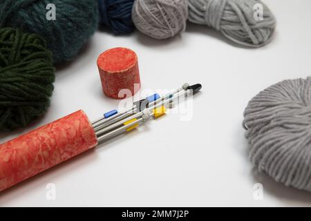 Hintergrund wird zusammengefügt. Set Stricknadeln, Garnstränge in Grau, Grün und Blau. Wollbälle auf weißem Hintergrund, Strickset im Retro-Stil. Stockfoto