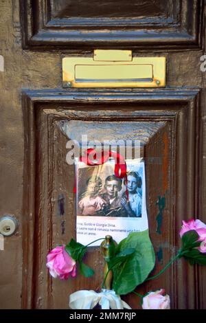 Am Holocaust-Gedenktag 2023 steckte eine anonyme Hand das Bild von drei Kindern und ein paar Blumen an die alte Tür, Nummer 5999 Cannaregio, in Venedig. Die Kinder wurden 1943 mit ihren Eltern und ihrem einjährigen Bruder nach Auschwitz deportiert. Sie waren 14, 10, 7 Jahre alt. Sie wurden am 26. Februar 1944 in Auschwitz mit ihrem einjährigen Bruder getötet. Vor einigen Jahren wurden 7 „Steine“ am Eingang ihres Hauses platziert. Auf dem Foto steht: " Anna, Guido und Giorgia Dina. Leone war ein Jahr alt und wir werden nie wissen, welches Gesicht er hatte. Stockfoto