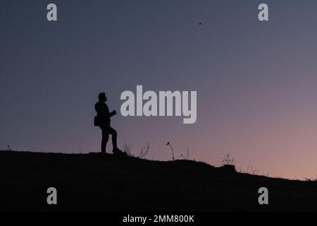 Junger männlicher Wanderer, der auf einem Berg steht und sich glücklich und inspiriert fühlt. Abenteuer, geistige Stärke und körperliche Gesundheit. Stockfoto