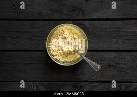 Gekochte Pasta mit Yushka auf einem Teller auf einem schwarzen Holztisch zum Mittagessen, Nudeln auf einem Teller auf dem Tisch Stockfoto