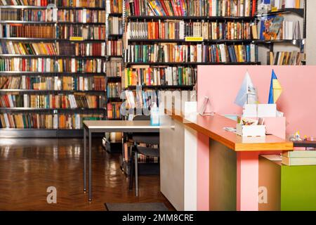 Der Schreibtisch der Rezeptionistin in der alten Bibliothek vor dem Hintergrund von verschwommenen Bücherregalen. Speicherplatz kopieren. Stockfoto