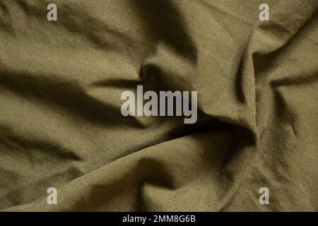 Dunkelgrüner, zerknitterter Stoff als Hintergrund, grüner Stoff Stockfoto