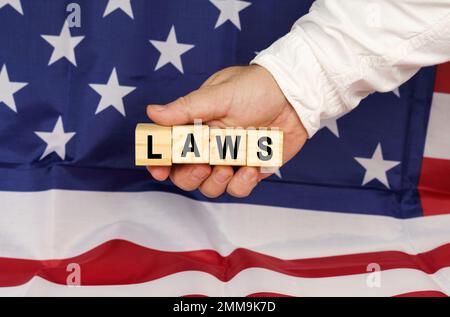 Geschäftskonzept. Vor dem Hintergrund der US-Flagge, die Hand eines Mannes mit Würfeln und dem Text "GESETZE" Stockfoto