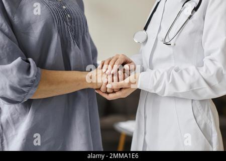 Covid-Genesungszentrum-Ärztin, die ältere Patienten an den Händen hält. Auflösung und hochwertige Fotos Stockfoto