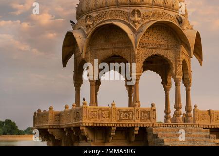 Aus nächster Nähe sehen Sie Chhatris und Schreine von hinduistischen Göttern und Göttinnen am Gadisar Lake, Jaisalmer, Rajasthan, Indien. Indoislamische Architektur, Sonnenuntergang. Stockfoto