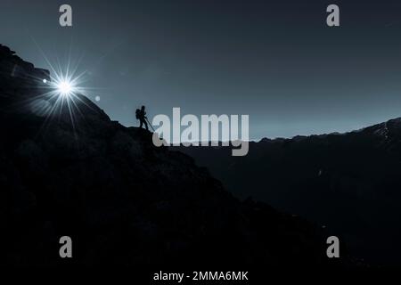 Bergsteiger auf felsigem Felsvorsprung mit Sonnenstern, im Hintergrund Südtiroler Berge, Naturn, Südtirol, Italien Stockfoto