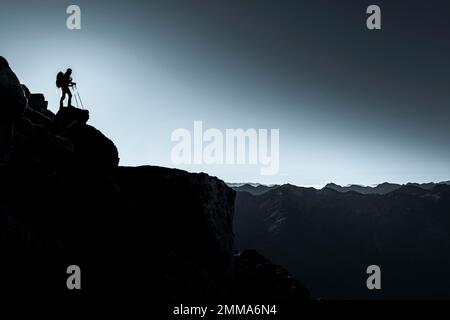 Bergsteiger auf felsigem Felsvorsprung mit Hintergrundbeleuchtung, Südtiroler Berge im Hintergrund, Naturn, Südtirol, Italien Stockfoto