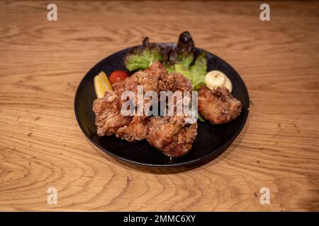 Im japanischen Restaurant werden Karaage oder japanisches gebratenes Huhn mit Mayo auf einem Holztisch serviert. Stockfoto