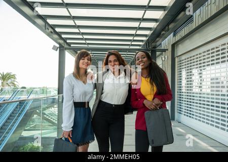 Drei Geschäftsfrauen posieren während eines Geschäftstreffens für ein Foto. Zwei von ihnen halten einen Laptop Stockfoto