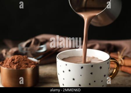 Heißes Kakaogetränk in den Becher auf dem Holztisch gießen Stockfoto