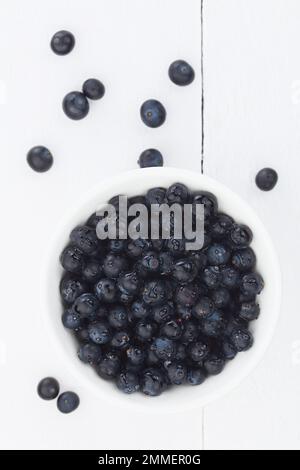 Frische rohe Patagonische Calafatbeeren (lat. Berberis heterophylla), fotografiert über Kopf auf Weißholz (selektiver Fokus) Stockfoto