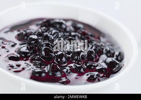 Frische hausgemachte Marmelade aus patagonischen Calafatbeeren (lat. Berberis heterophylla), serviert in einer weißen Schüssel (selektiver Fokus) Stockfoto