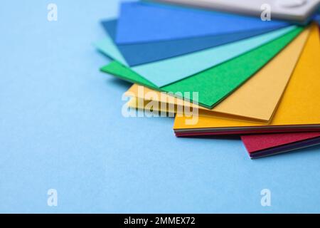 Mehrfarbige Papierbögen auf hellblauem Hintergrund, Platz für Text. Regenbogenpalette Stockfoto