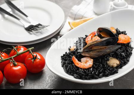 Köstliches schwarzes Risotto mit Meeresfrüchten auf einem Marmortisch Stockfoto