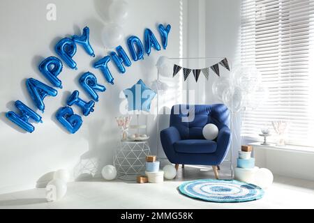 Phrase HAPPY BIRTHDAY aus blauen Ballonbuchstaben im dekorierten Zimmer Stockfoto