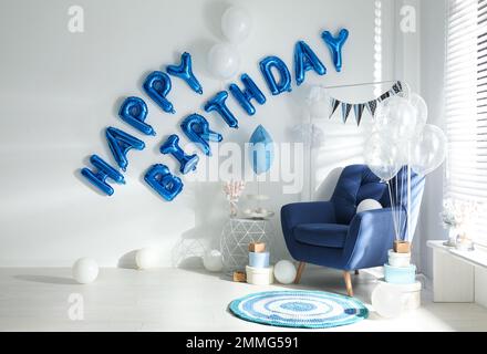 Phrase HAPPY BIRTHDAY aus blauen Ballonbuchstaben im dekorierten Zimmer Stockfoto