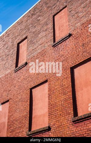 Alte Backsteinmauer mit Backsteinfenstern. Rote Backsteinwand eine Fabrik mit vier Ziegelfenstern mit Platz für Text. Backsteinmauer. Straßenfoto, n Stockfoto