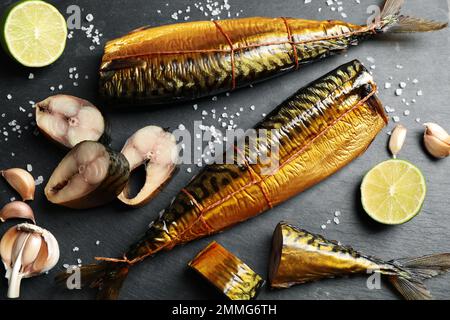 Flache Liegezusammensetzung mit Räucherfisch auf schwarzem Tisch Stockfoto