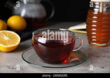 Frischer Tee mit Honig und Zitrone auf hellgrauem Tisch, Nahaufnahme Stockfoto