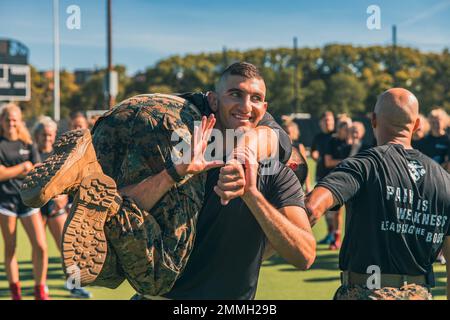 Midshipman William Attisha mit dem Naval Reserve Officers Training Corps - Massachusetts Institute of Technology, demonstriert eine ordnungsgemäße Feuerwehrmann tragen für das Feldhockey-Team der Harvard University bei einem Team-und Führungsseminar von den Marines mit Officer Selection Station Boston in Cambridge, Massachusetts, 17. September 2022 statt. Das Hockeyteam nahm am Kampffitnesstest des Marine Corps Teil, der aus einem 880-Meter-Lauf, Munitionsliften und einem Manöver unter Feuerübung besteht. Auf jede Veranstaltung folgten Teamarbeit und Führungsgespräche. Stockfoto