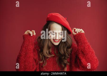 Fröhlichen Valentinstag. Glückliche moderne Frau mit langen welligen Haaren in rotem Pullover und Baskenmütze. Stockfoto