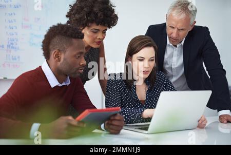 Eine kurze Vorführung. Eine Gruppe von Geschäftsleuten, die ihre Arbeit über ein Notebook diskutieren. Stockfoto