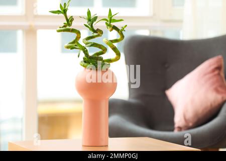 Stilvolle Vase mit grünen Bambusstielen auf dem Tisch im Zimmer Stockfoto