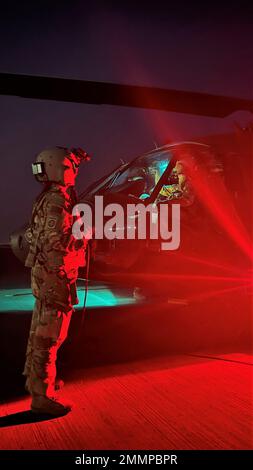 USA Army 1. Sergeant Amy Klemm, UH-60m Crew Chief and Flight Instructor for Bravo Company, 3. Bataillon, 142. Aviation Regiment, Assault Helicopter Battalion, verbunden mit 36. Combat Aviation Brigade (Stand), hat die Triebwerke Nummer 1 für ihre Piloten freigegeben, Chief Warrant Officer 2 Christopher Gallant und Chief Warrant Officer 2 Christopher Hansen, Während der UH-60m Black Hawk Startup in Camp Buehring, Kuwait, 21. September 2022. Die Freigabe von Triebwerken während des Starts ist für die Sicherheit der Besatzung und des Personals in der Nähe des Flugzeugs von entscheidender Bedeutung. Klemm und ihre Crew haben die Landezonen nachts in der Nähe überprüft Stockfoto