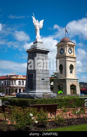 War Memorial und Uhrenturm, Manchester Square, Feilding, Manawatu, North Island, Neuseeland. Das Feilding Hotel in der Ferne. Stockfoto