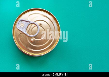 Leicht zu öffnender Deckel aus Metall auf grünem Hintergrund. Draufsicht der Blechdose mit isoliertem Ringzug auf grünem Hintergrund mit Kopierbereich. Nahaufnahme Stockfoto