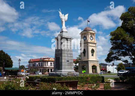 War Memorial und Uhrenturm, Manchester Square, Feilding, Manawatu, North Island, Neuseeland. Das Feilding Hotel in der Ferne. Stockfoto