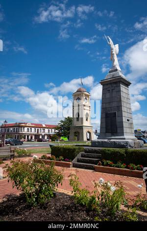 War Memorial und Uhrenturm, Manchester Square, Feilding, Manawatu, North Island, Neuseeland. Das Feilding Hotel in der Ferne. Stockfoto