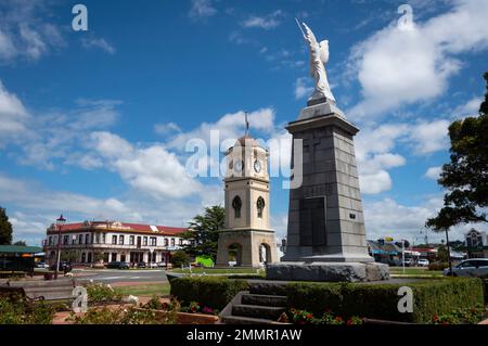 War Memorial und Uhrenturm, Manchester Square, Feilding, Manawatu, North Island, Neuseeland. Das Feilding Hotel in der Ferne. Stockfoto